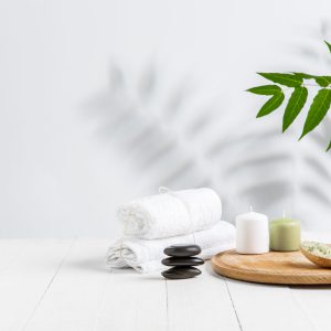 Beautiful spa composition on massage table in wellness center, copyspace. Accessories for relaxing treatments and personal care. Towels, oils, serum, sea salts and scrubs. Decorative candles.